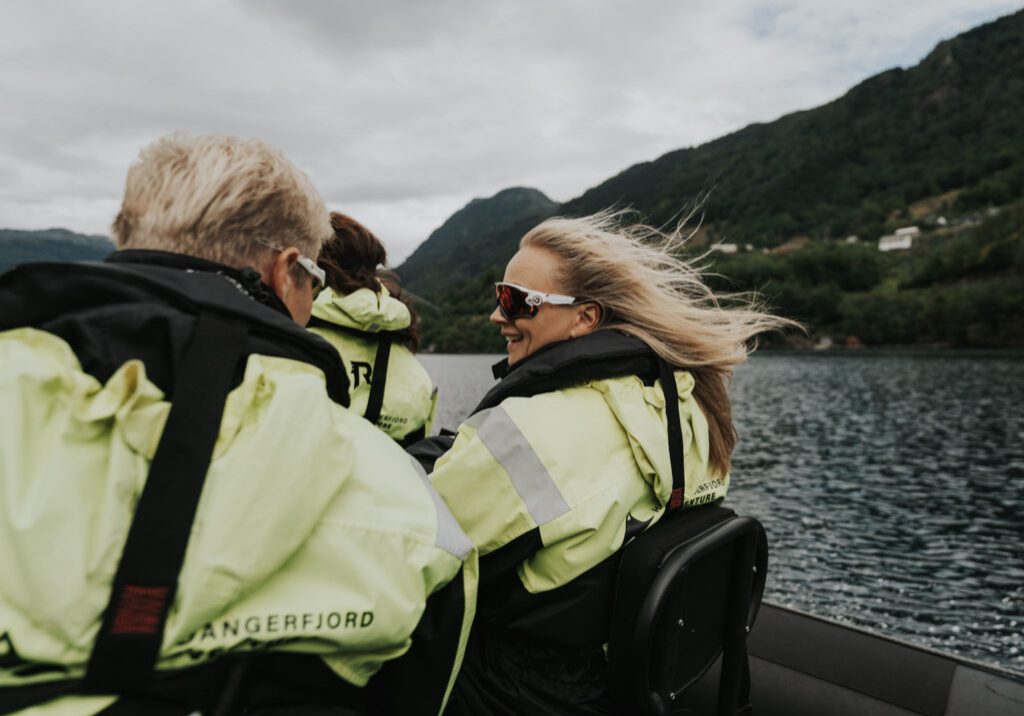 Three passengers of a RIB boat sitting in a moving boat with wind in their hair.